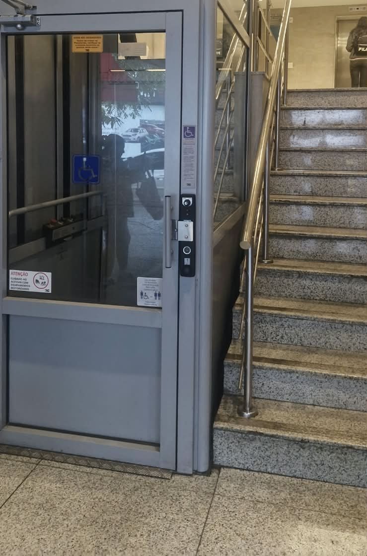Plataforma elevatória acessível ao lado da escada de entrada do prédio