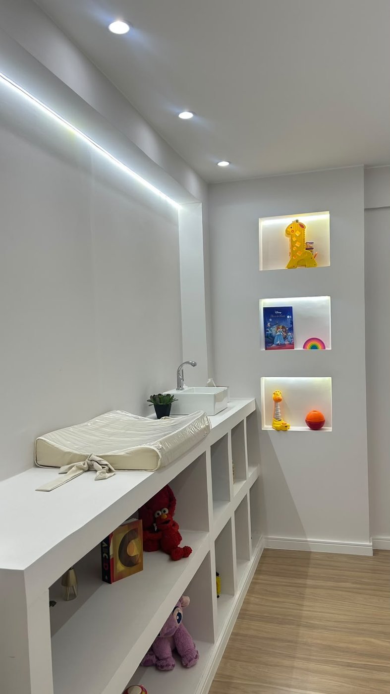 Espaço infantil com bancada, pia, nichos iluminados e prateleiras com brinquedos